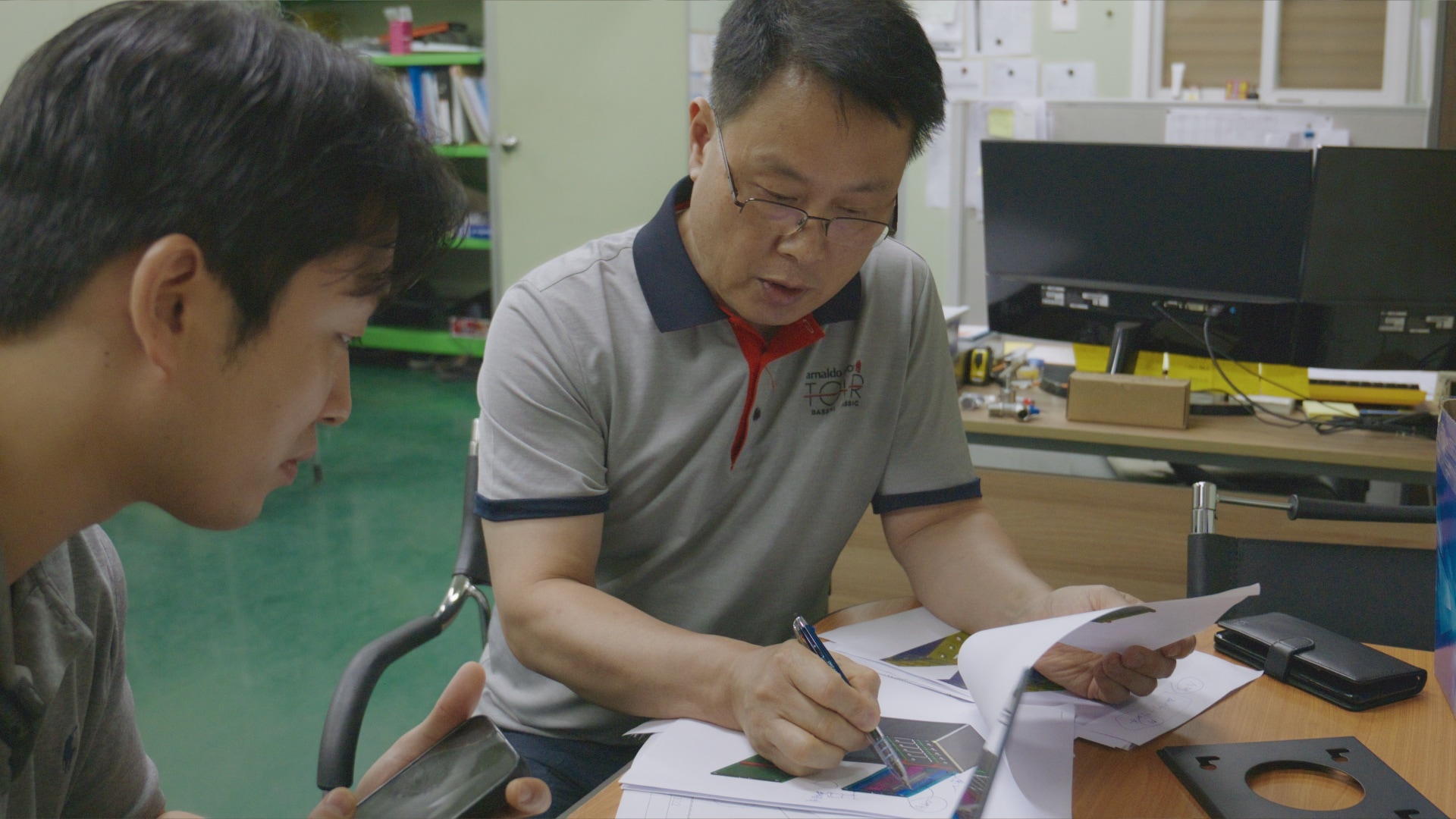 브링크 담당자와 제작 전문가가 설계 도면과 가공 부품을 함께 검토하는 모습